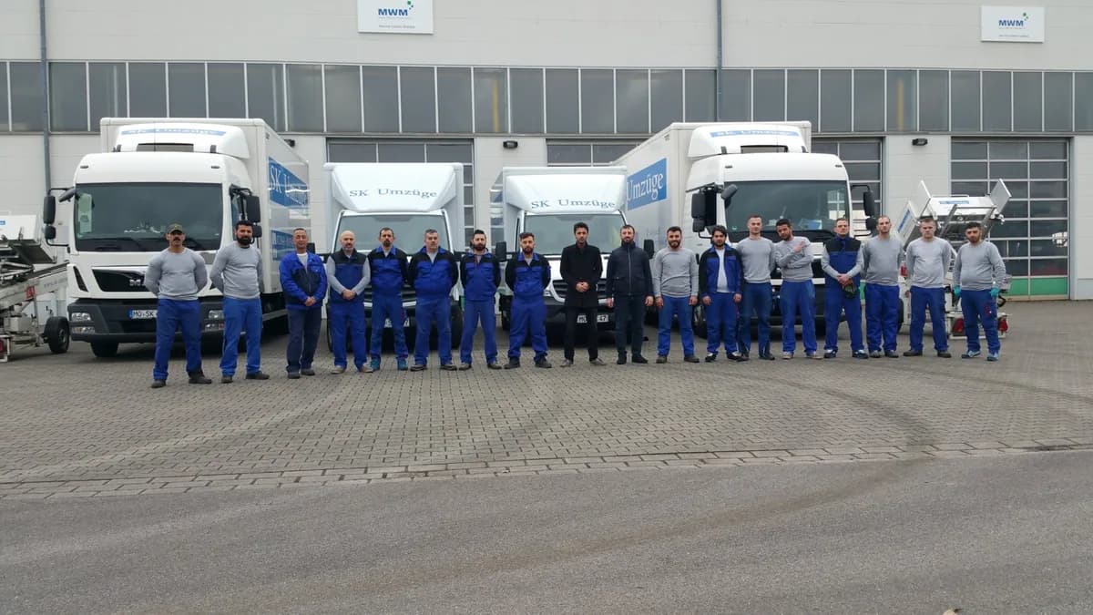 Team von SK-Umzüge vor Umzugswagen und Möbelliften